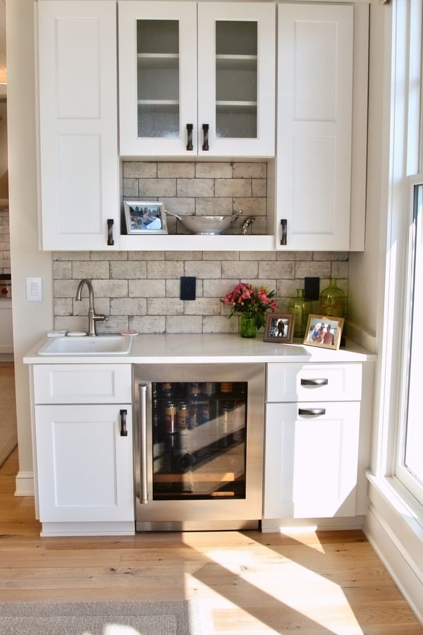 Built-in beverage bar with glass-front upper cabinets, a bar sink, and an undercounter beverage cooler