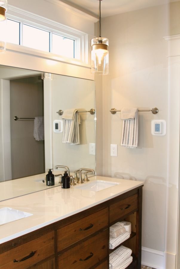 Bathroom with a wood vanity, white countertop, pendant light, and transom windows