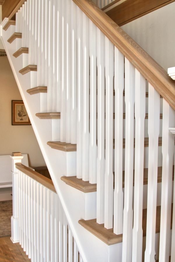 Staircase with white balusters, a wood handrail, and wood treads