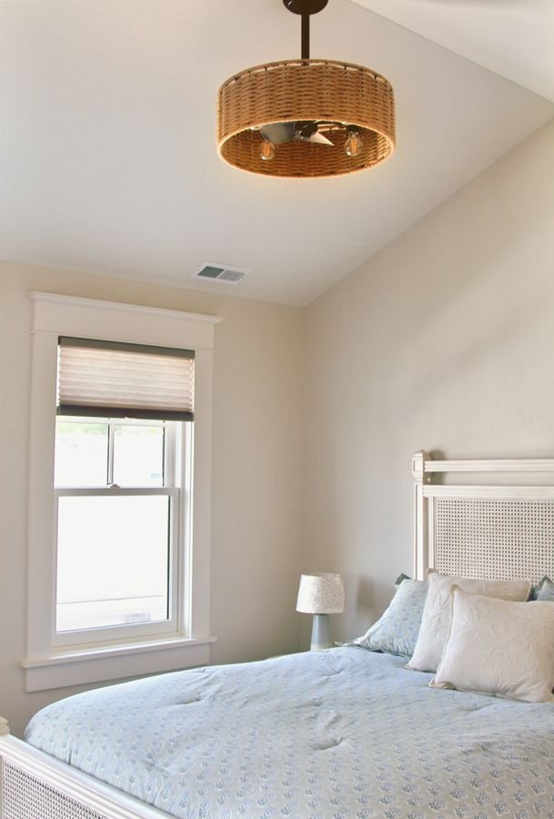 Guest bedroom with a vaulted ceiling, a woven ceiling fixture, and a cane headboard