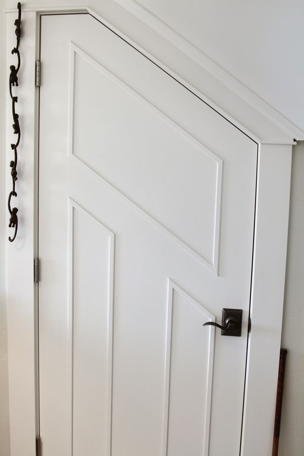Custom panel door cut to follow the slope of the stair above it