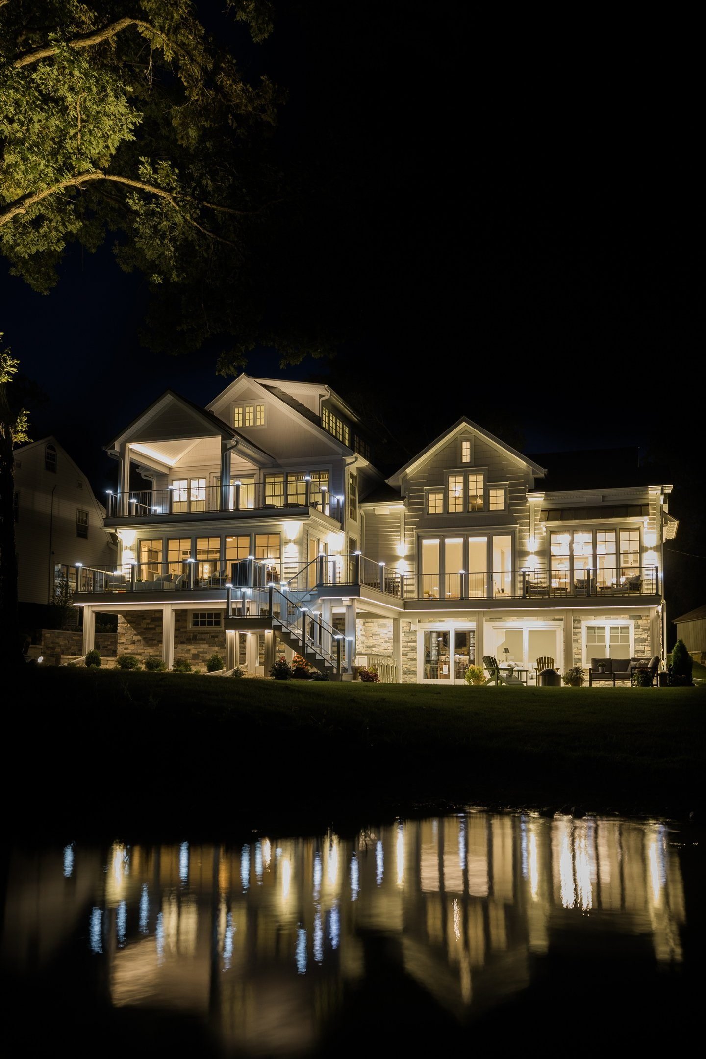 Custom lakeside home by Monien Construction lit at dusk over the water