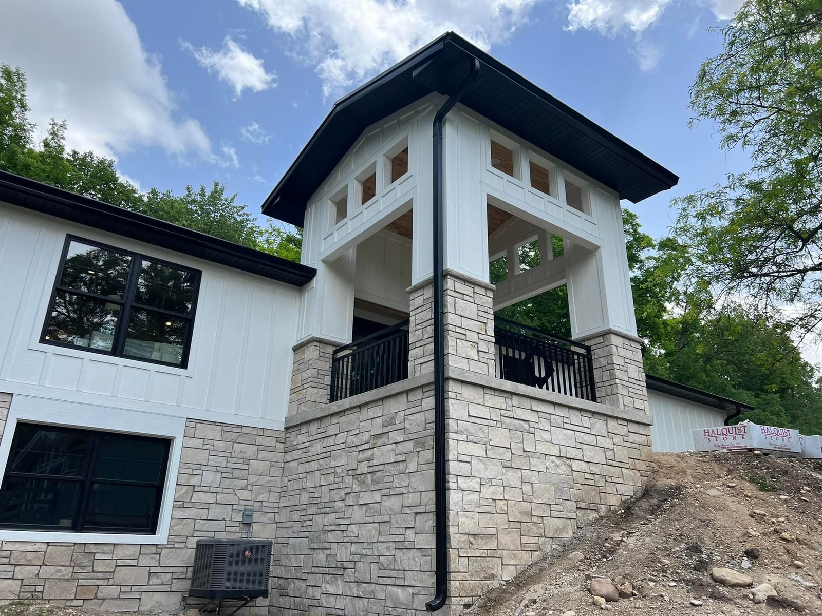 Carriage house tower under construction with exposed stone and bare grade