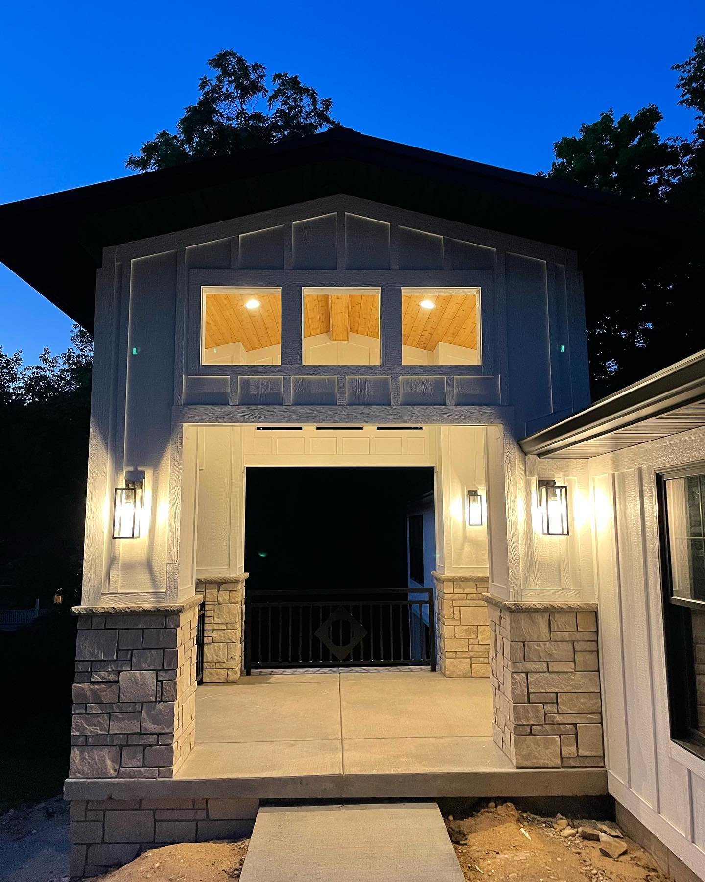 Finished carriage house lit warmly in the evening with completed drive