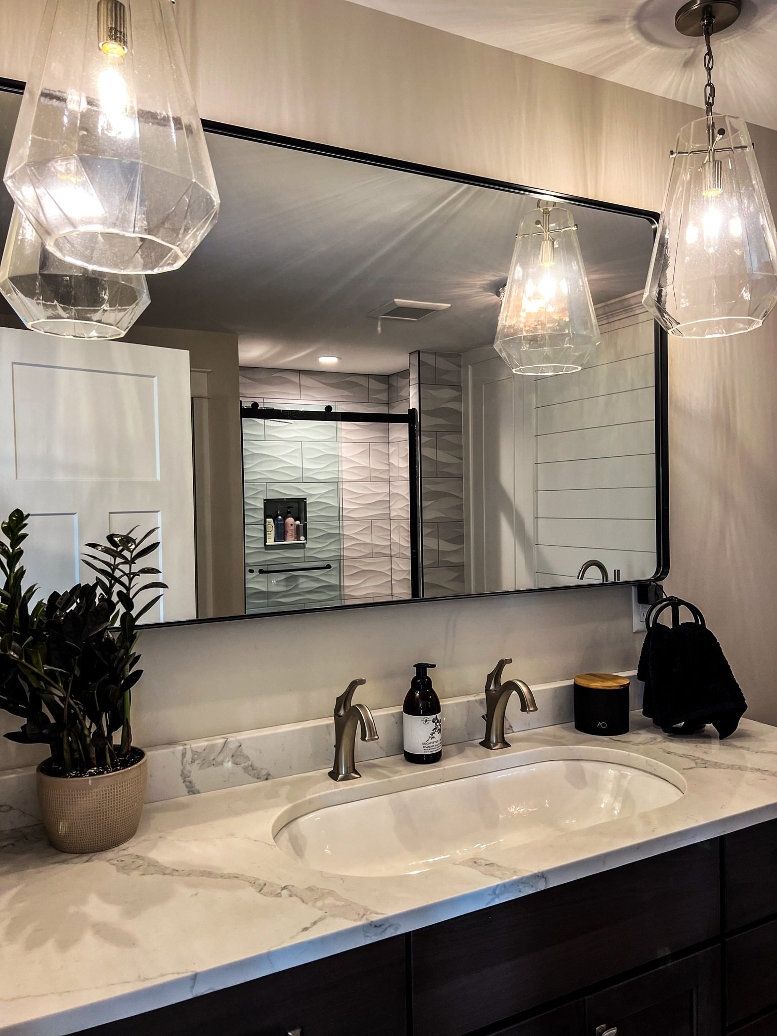 Renovated bath with double vanity, marble counter, and glass pendant lighting