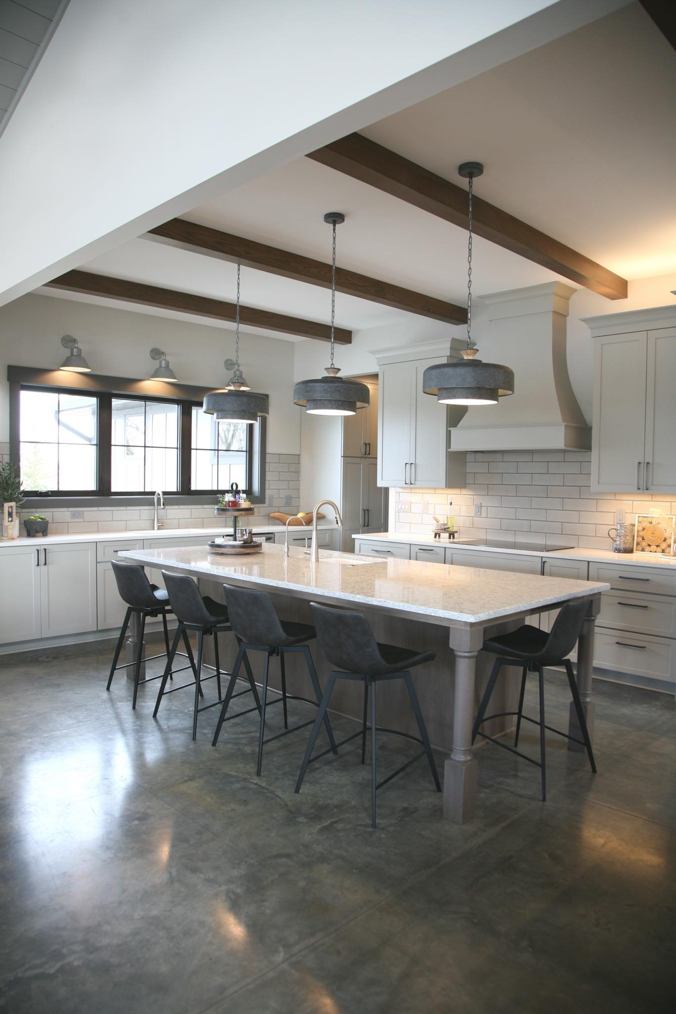 Renovated open kitchen with oversized island, beamed ceiling, and polished concrete floor