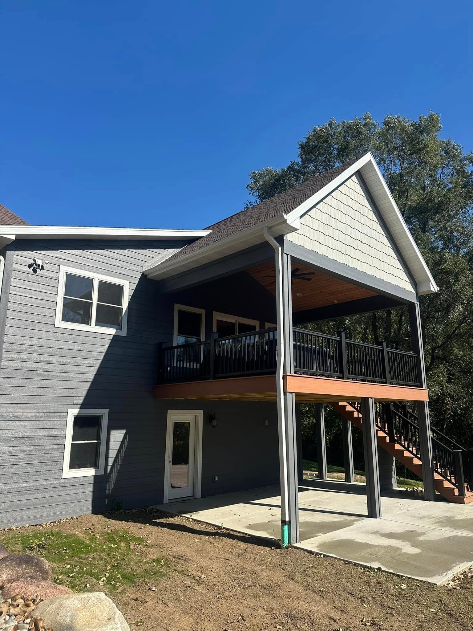 Elevated deck addition with covered lower patio on a gray lake house