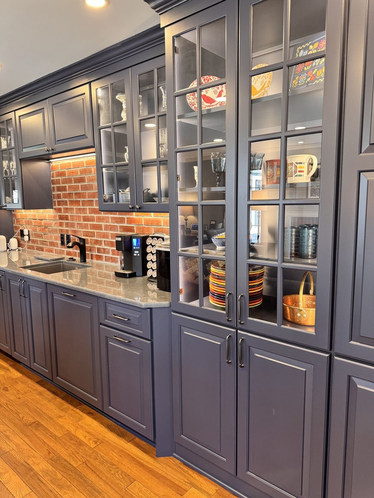 Navy built-in cabinetry with glass doors and a brick backsplash from a Delavan renovation