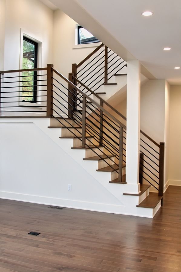 Open staircase with wood treads, a wood handrail, and horizontal black metal rails