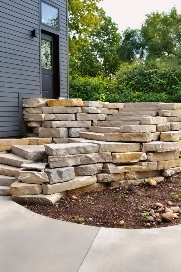 Natural stone steps and terraced outcropping beside the home's dark siding