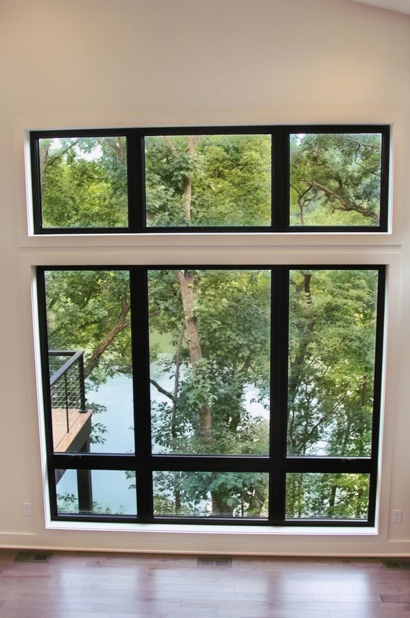 Black-framed window wall with the lake visible through the trees